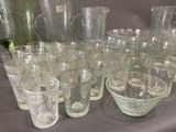 many glasses and pitchers on a table with a pitcher