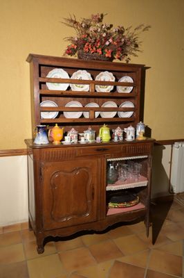 une armoire en bois sur laquelle sont posées des assiettes, dans une pièce