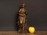 a statue of a woman holding an apple on a table