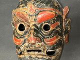 an image of a wooden mask with red and black paint