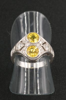 silver ring with yellow and white stones on a black surface