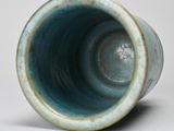 a close up of a blue vase on a white surface