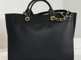 un sac fourre-tout en cuir noir avec des chaînes dorées aux anses