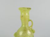 a green glass vase with a handle on a table