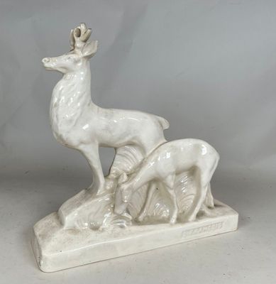 a white statue of a deer and a baby deer on a rock