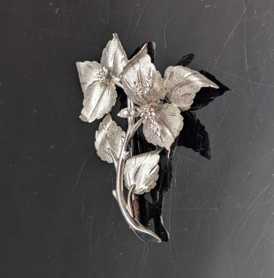 une broche en argent ornée de fleurs sur un fond noir
