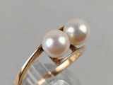 a close up of a gold ring with two pearls on it