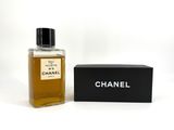 un flacon de parfum Chanel posé à côté d'une boîte sur une surface blanche