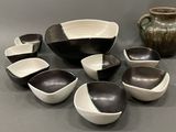 many bowls and bowls sitting on a table next to a vase