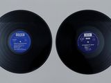 two black vinyl records sitting on top of a white surface