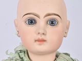 a doll with a bald head wearing a green dress