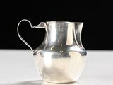 a silver pitcher sitting on a table with a black background
