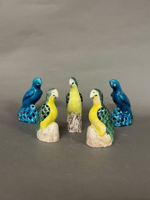 trois petites figurines d'oiseaux perchés sur une souche en bois