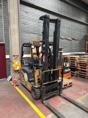 un chariot élévateur garé dans un entrepôt, avec des palettes en arrière-plan