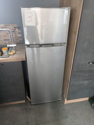 a silver refrigerator in a small kitchen with a sink