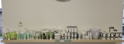 many toothbrushes lined up on a shelf with a clock on the wall