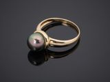 a gold ring with a black pearl on a black surface