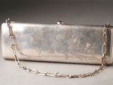 a silver purse with a chain around it on a table