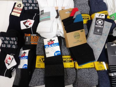 Plusieurs paires de chaussettes pour homme sont disposées sur un lit.