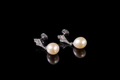 une paire de boucles d'oreilles en perles et diamants sur fond noir
