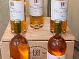 four bottles of wine sit in a wooden crate on a table