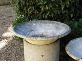 a concrete birdbath sitting next to a table in a garden