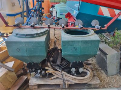 deux conteneurs verts posés sur une palette à côté d'un bateau rouge et bleu