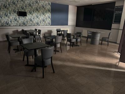 des tables et des chaises dans une grande pièce avec un tableau noir accroché au mur