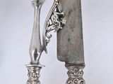 two silver spoons and a knife hanging on a wall