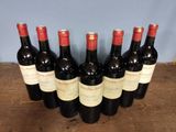 six bottles of red wine lined up on a wooden table