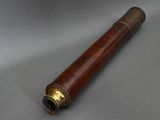 an antique telescope with a wooden case and brass fittings on a gray surface