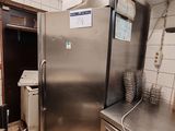 a stainless steel refrigerator in a kitchen with a lot of dishes on the counter