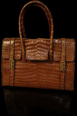 an image of a brown alligator skin purse on a black surface