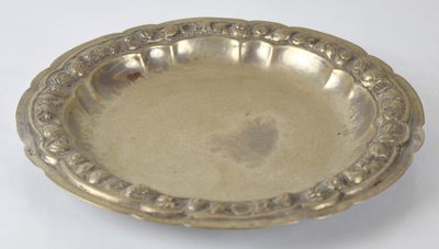 un plat en argent ancien posé sur une table blanche, sur fond blanc