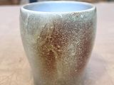 un gros plan d'une tasse posée sur une table, avec un mur en pierre en arrière-plan