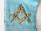 embroidered masonic square and compass symbol on a blue pillow