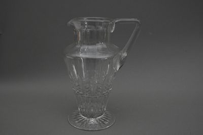 un pichet en verre transparent muni d'une anse, posé sur une surface grise