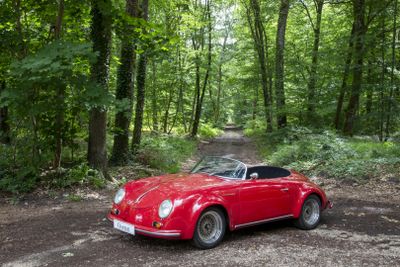 a red car parked in the middle of a forest