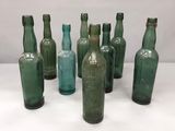 Plusieurs bouteilles en verre vert sont alignées sur une surface blanche