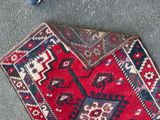 a red and blue rug on the floor next to a pair of scissors