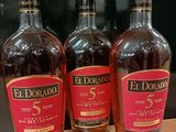 Trois bouteilles de whisky El Dorado 5 ans d'âge sont posées sur une table