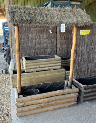 une petite cabane au toit de chaume avec quelques bacs de foin