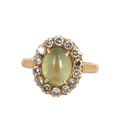 un gros plan d'une bague en or sertie d'une pierre verte entourée de diamants blancs