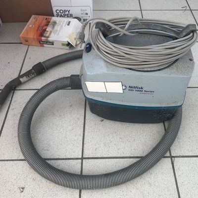 un aspirateur posé au sol, muni d'un tuyau