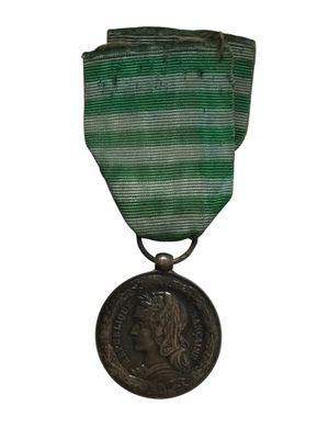 une vieille médaille avec un ruban vert sur fond blanc