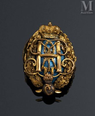 a close up of a gold and blue broochle on a black surface