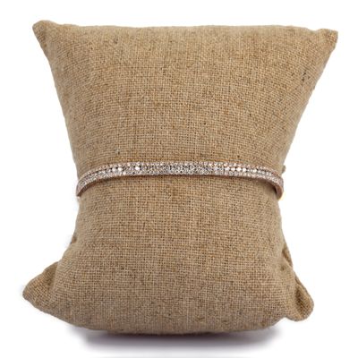 un bracelet en diamants posé sur un coussin, sur fond blanc