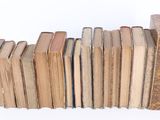 several old books are stacked on top of each other on a white surface