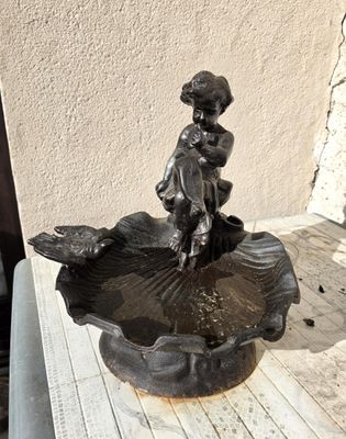 une petite statue représentant une fillette assise sur une fontaine