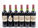 six bouteilles de vin rouge alignées sur une surface blanche